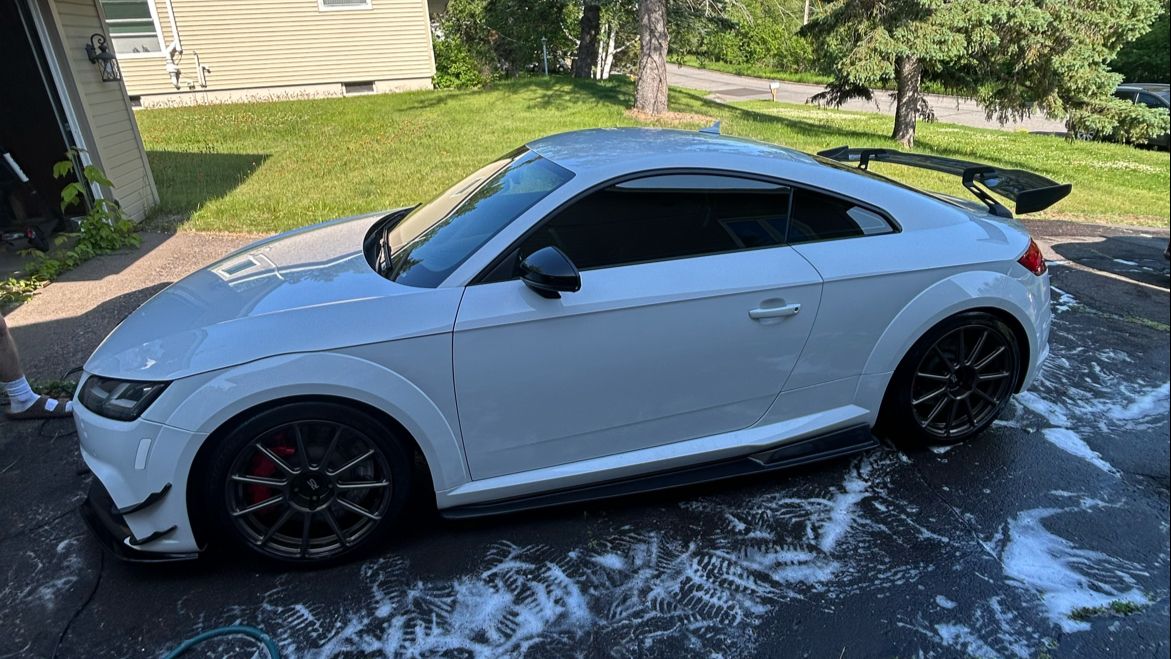 A light blue Audi TT part-way through a wash on a Superior, Wisconsin driveway, suds running across the asphalt