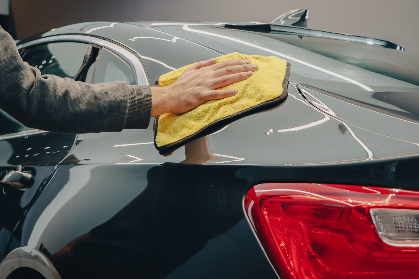 A detailer spraying a panel and wiping it down with a microfibre towel