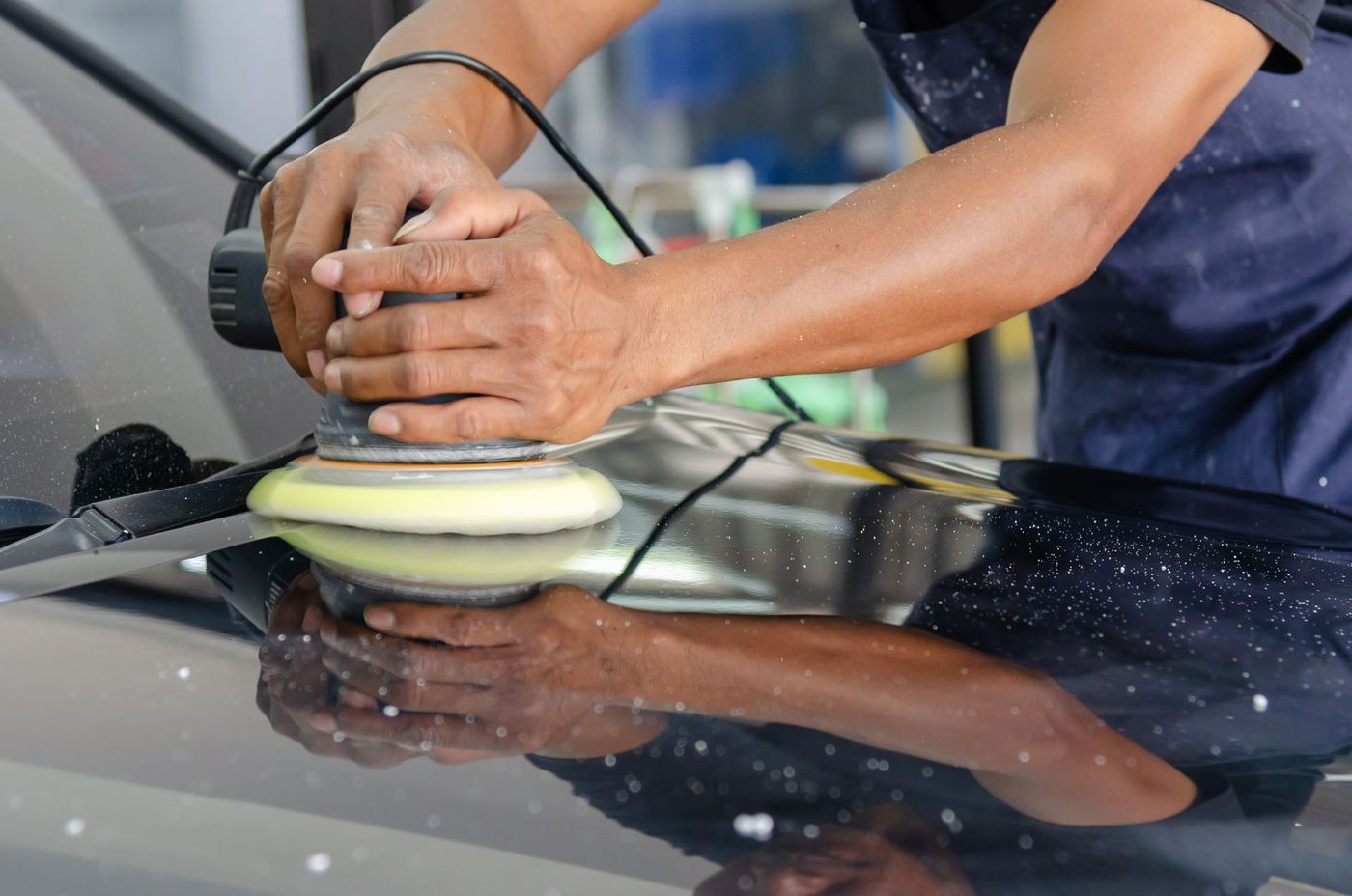 A dual-action polisher being run across a car's paint